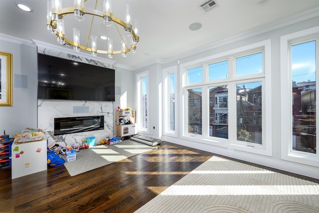 living room with a premium fireplace, dark hardwood / wood-style flooring, a chandelier, and ornamental molding