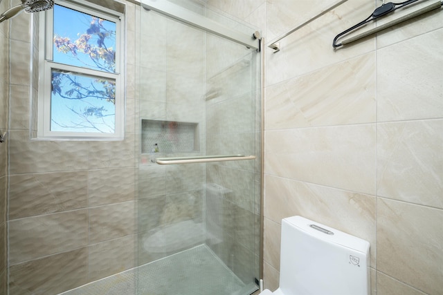 bathroom with a shower with shower door and toilet