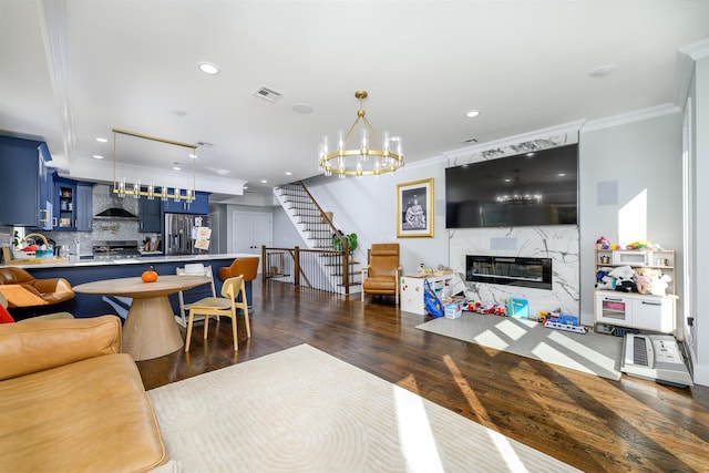 living room with a fireplace, dark wood-type flooring, a chandelier, and crown molding