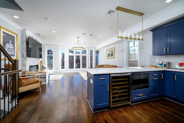 kitchen featuring wine cooler, kitchen peninsula, decorative light fixtures, and blue cabinets