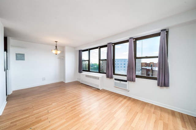 empty room with light hardwood / wood-style flooring, radiator, and a wall unit AC