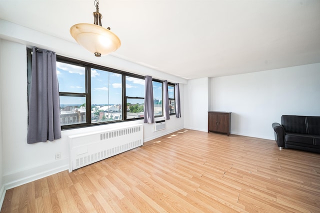 unfurnished living room with radiator heating unit and light hardwood / wood-style floors