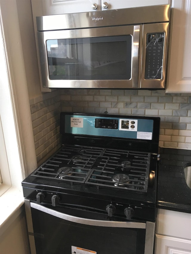 18 74th St Unit D5, North Bergen, NJ 07047 - kitchen view of stainless steel appliances, decorative backsplash, white cabinetry, and dark countertops