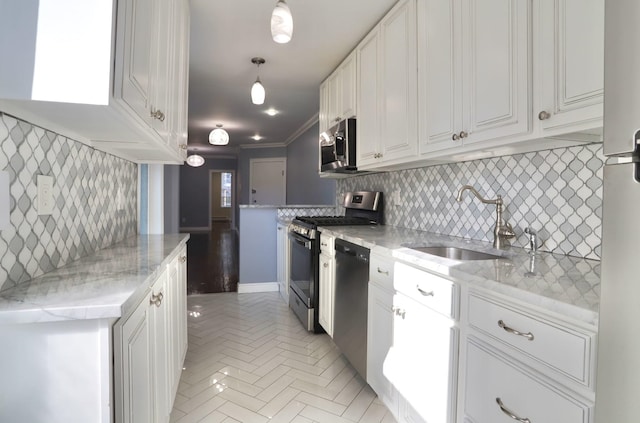 kitchen with white cabinets, appliances with stainless steel finishes, decorative light fixtures, light stone countertops, and a sink