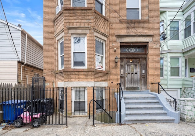 property entrance with a gate, brick siding, and fence