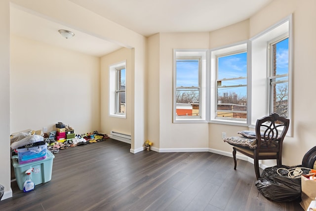 interior space with a baseboard heating unit, dark wood-style flooring, and baseboards