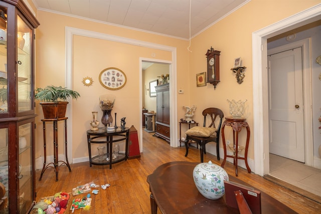 sitting room with ornamental molding and light wood-type flooring