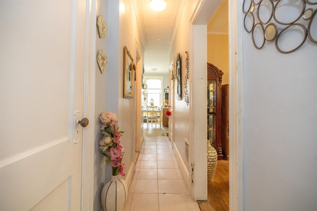 corridor with crown molding and light tile patterned floors