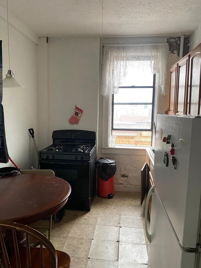 6414 Park Ave Unit 8, West New York, NJ 07093 - kitchen featuring freestanding refrigerator, black range with gas cooktop, and a textured ceiling
