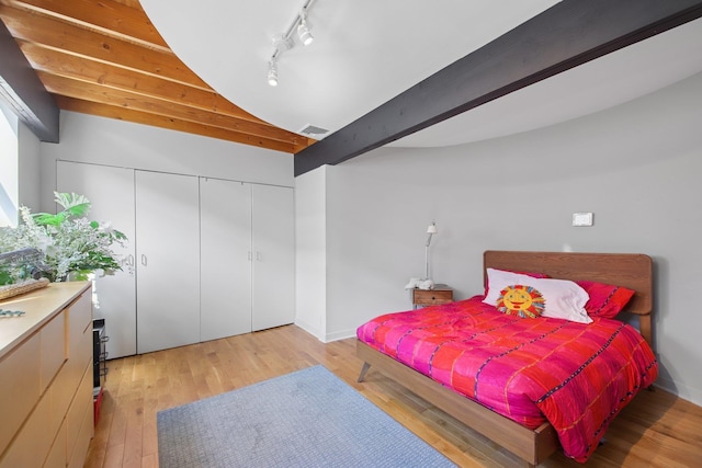 bedroom with rail lighting, lofted ceiling, light wood-type flooring, visible vents, and a closet