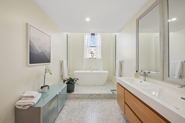 bathroom with double vanity, a freestanding tub, a sink, and tile patterned floors