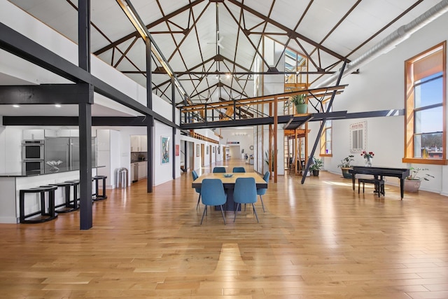 interior space with high vaulted ceiling, baseboards, and light wood finished floors