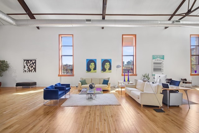 living area with wood-type flooring, plenty of natural light, and beam ceiling
