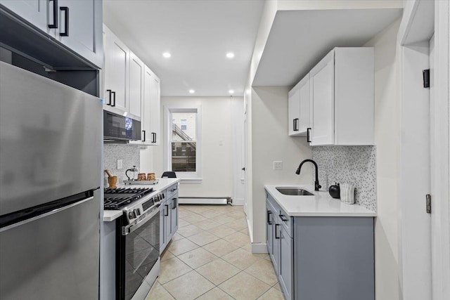 kitchen with white cabinetry, sink, stainless steel appliances, baseboard heating, and backsplash