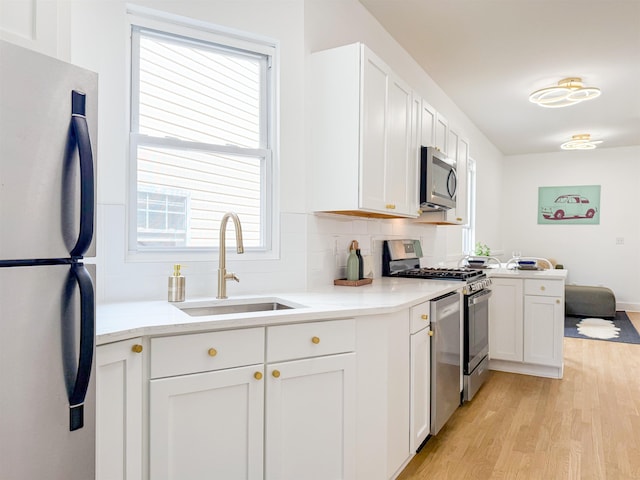 kitchen featuring a healthy amount of sunlight, light wood finished floors, stainless steel appliances, and a sink