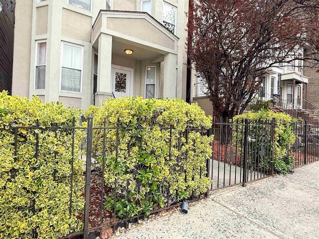 view of exterior entry with stucco siding and fence