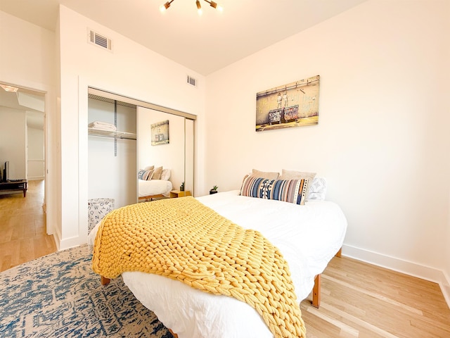 bedroom featuring a closet, wood finished floors, visible vents, and baseboards