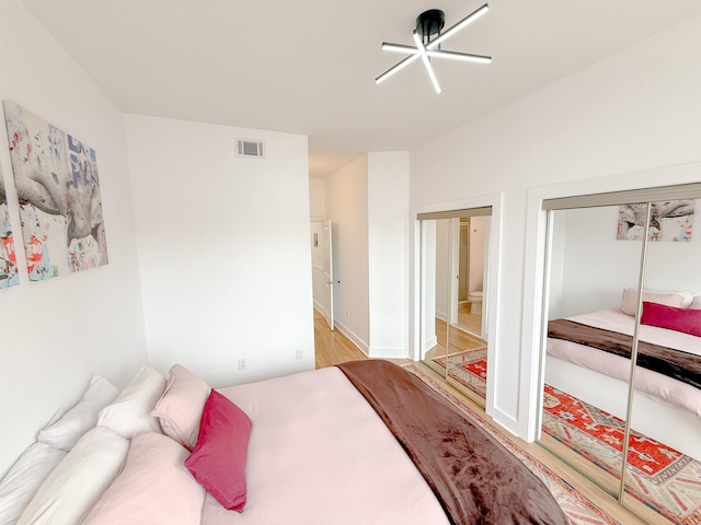bedroom with wood finished floors, a ceiling fan, and visible vents