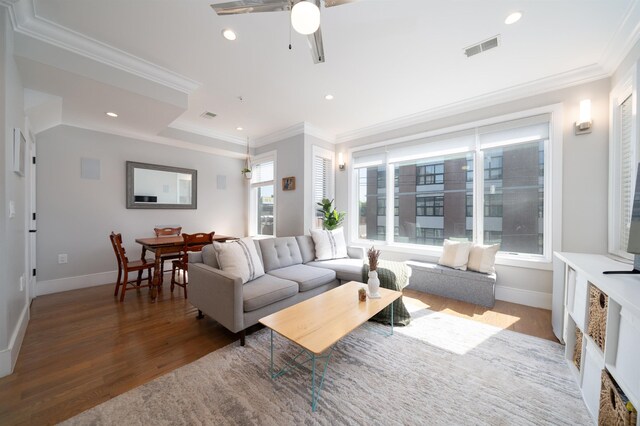 living area with crown molding, baseboards, visible vents, and wood finished floors