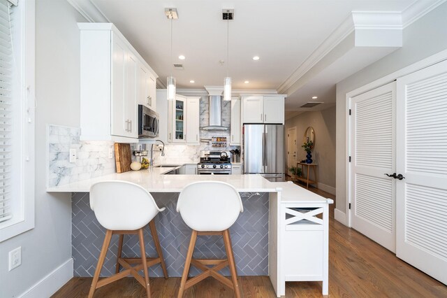 kitchen with dark wood-style flooring, appliances with stainless steel finishes, wall chimney exhaust hood, a peninsula, and tasteful backsplash