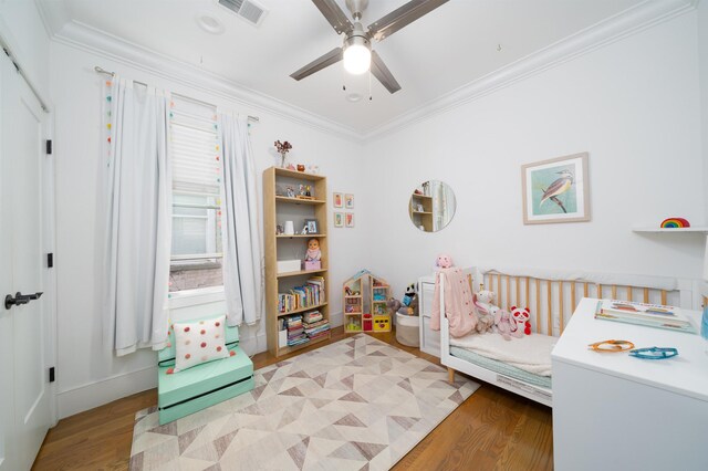 bedroom featuring crown molding, a ceiling fan, wood finished floors, and visible vents