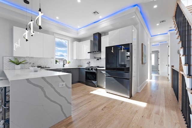 kitchen featuring visible vents, gas range, smart refrigerator, modern cabinets, and wall chimney exhaust hood