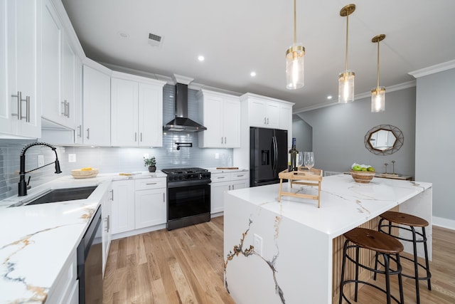 kitchen featuring wall chimney exhaust hood, sink, black appliances, a center island, and white cabinetry