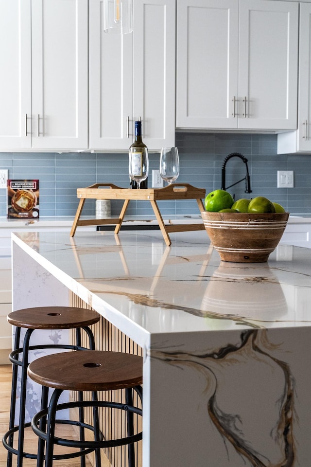 details with a kitchen breakfast bar, decorative backsplash, and white cabinetry