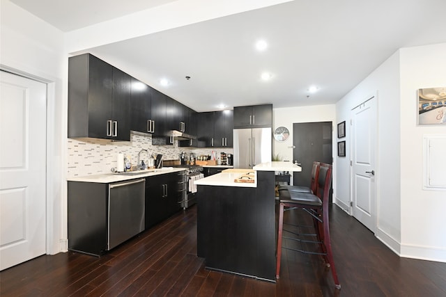 kitchen with a kitchen bar, high quality appliances, dark cabinets, and light countertops