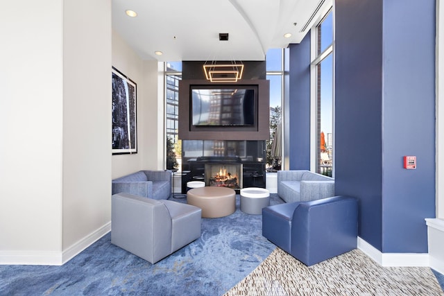 living area with recessed lighting, a large fireplace, baseboards, and floor to ceiling windows