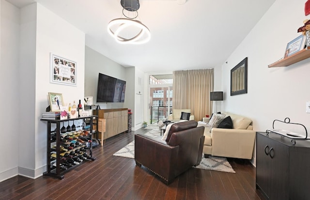 living area with baseboards and dark wood-type flooring