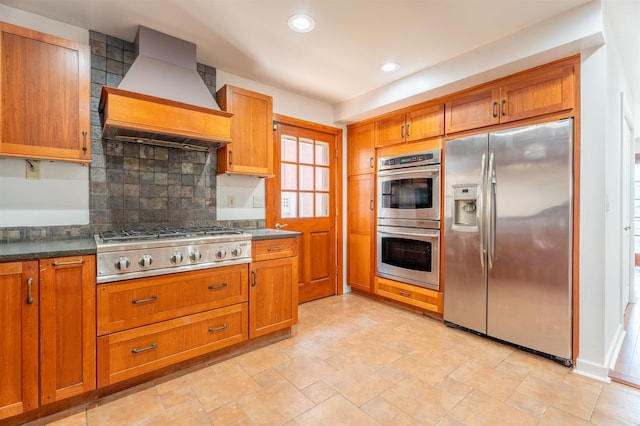 238 Undercliff Ave, Edgewater, NJ 07020 - kitchen with appliances with stainless steel finishes, custom range hood, backsplash, brown cabinetry, and dark countertops