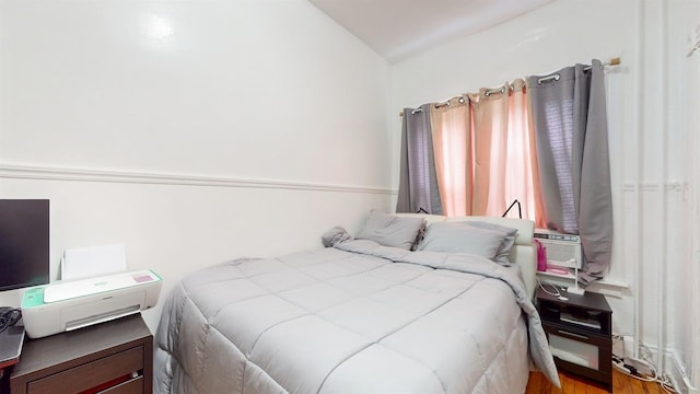 bedroom featuring cooling unit, hardwood / wood-style flooring, and vaulted ceiling