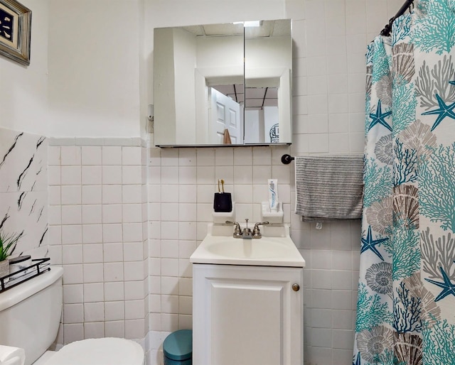 bathroom featuring toilet, vanity, and tile walls