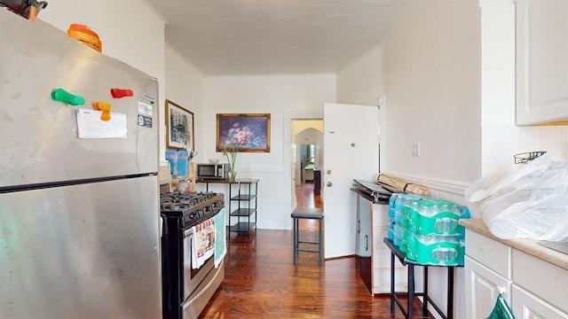 kitchen featuring crown molding, stainless steel appliances, dark hardwood / wood-style flooring, decorative backsplash, and white cabinets