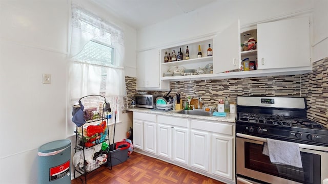 kitchen featuring tasteful backsplash, light stone counters, stainless steel appliances, white cabinetry, and dark parquet floors