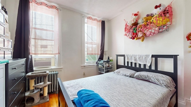 bedroom with radiator, cooling unit, crown molding, and hardwood / wood-style flooring