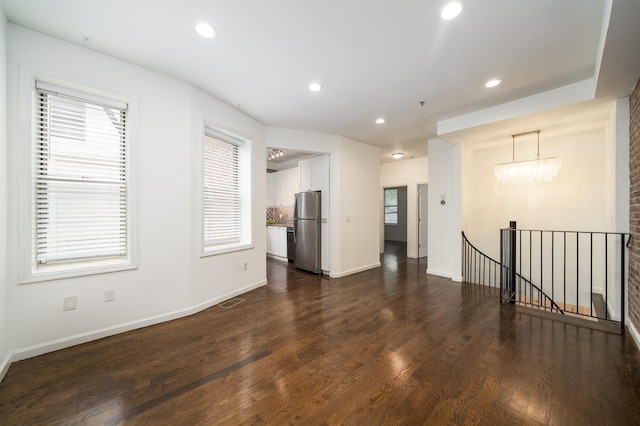 spare room with an inviting chandelier, baseboards, dark wood-type flooring, and recessed lighting