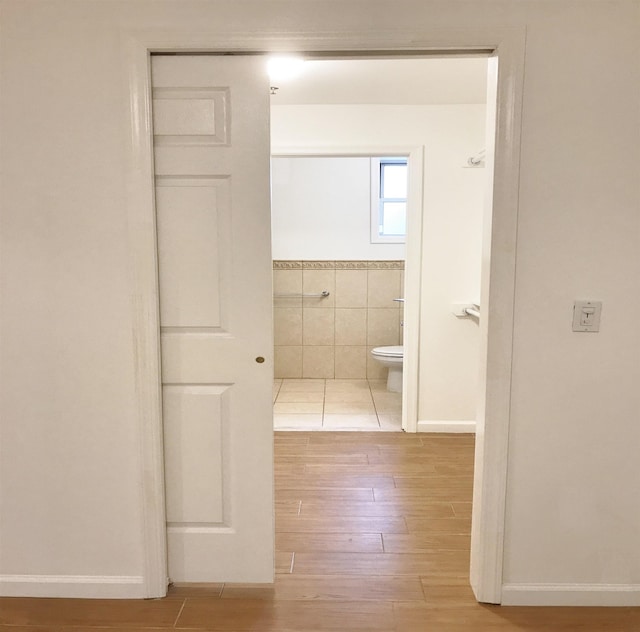 bathroom featuring toilet, tile walls, and wood finished floors