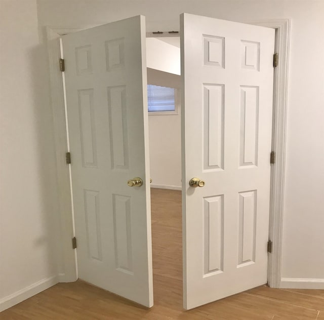 corridor with light wood-style flooring and baseboards