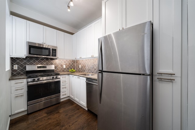 kitchen featuring stainless steel appliances, decorative backsplash, dark wood-type flooring, white cabinetry, and a sink