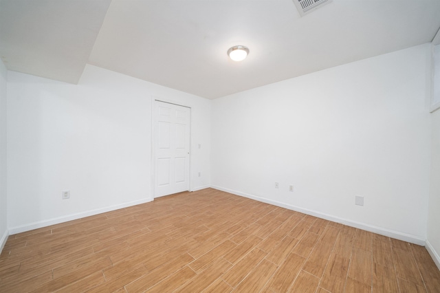 spare room with light wood-type flooring, visible vents, and baseboards