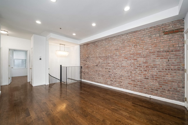 empty room with brick wall, baseboards, wood finished floors, and recessed lighting