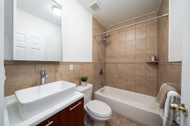 bathroom with visible vents, toilet, vanity, tile walls, and shower / bathing tub combination