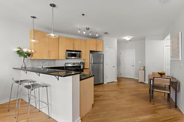 83 Monroe St Unit 3A, Hoboken, NJ 07030 - kitchen featuring a breakfast bar area, dark countertops, a peninsula, stainless steel appliances, and light wood-style flooring
