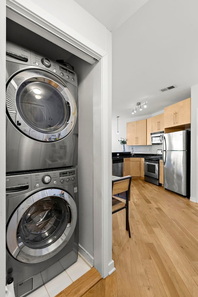 83 Monroe St Unit 3A, Hoboken, NJ 07030 - washroom with visible vents, laundry area, stacked washer / dryer, rail lighting, and light wood-style flooring