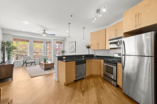 83 Monroe St Unit 3A, Hoboken, NJ 07030 - kitchen featuring light brown cabinetry, dark countertops, light wood-style floors, stainless steel appliances, and a peninsula