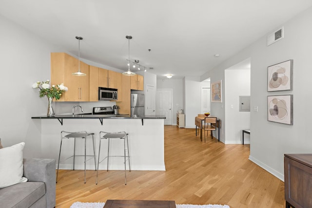 83 Monroe St Unit 3A, Hoboken, NJ 07030 - kitchen with dark countertops, appliances with stainless steel finishes, a kitchen breakfast bar, a peninsula, and visible vents