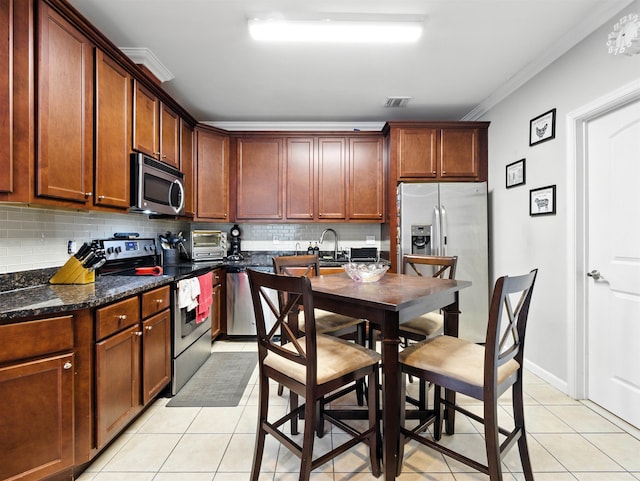 5808 Washington St Unit 406A, West New York, NJ 07093 - kitchen featuring appliances with stainless steel finishes, light tile patterned floors, decorative backsplash, crown molding, and dark stone counters