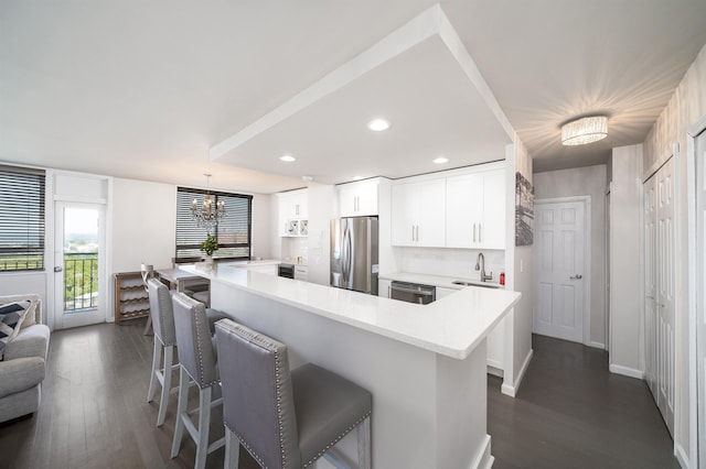 kitchen with a kitchen bar, sink, decorative light fixtures, stainless steel appliances, and white cabinets